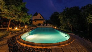 Una piscina con cubierta de madera y una casa al fondo.