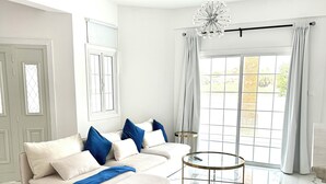 A modern living room with a beige sofa, a coffee table, and a chandelier.
