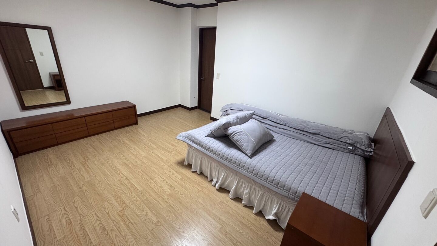 Un dormitorio con una cama, un tocador, un espejo y una puerta.