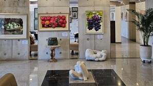 Um hall moderno com piso de mármore, obras de arte emolduradas, um vaso decorativo e uma escultura.