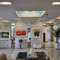 Um hall moderno com piso de mármore, obras de arte emolduradas, um vaso decorativo e uma escultura.