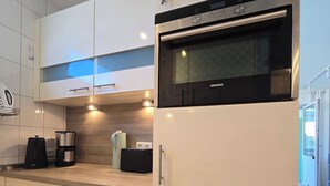 A modern kitchen with white cabinetry, a built-in microwave, and a coffee maker.