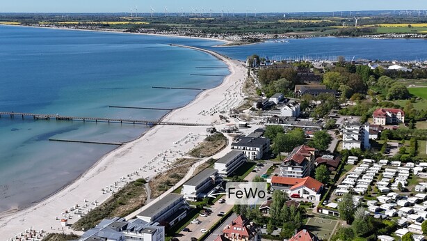 An aerial view of a coastal town with a beach, a pier, and a caravan park.