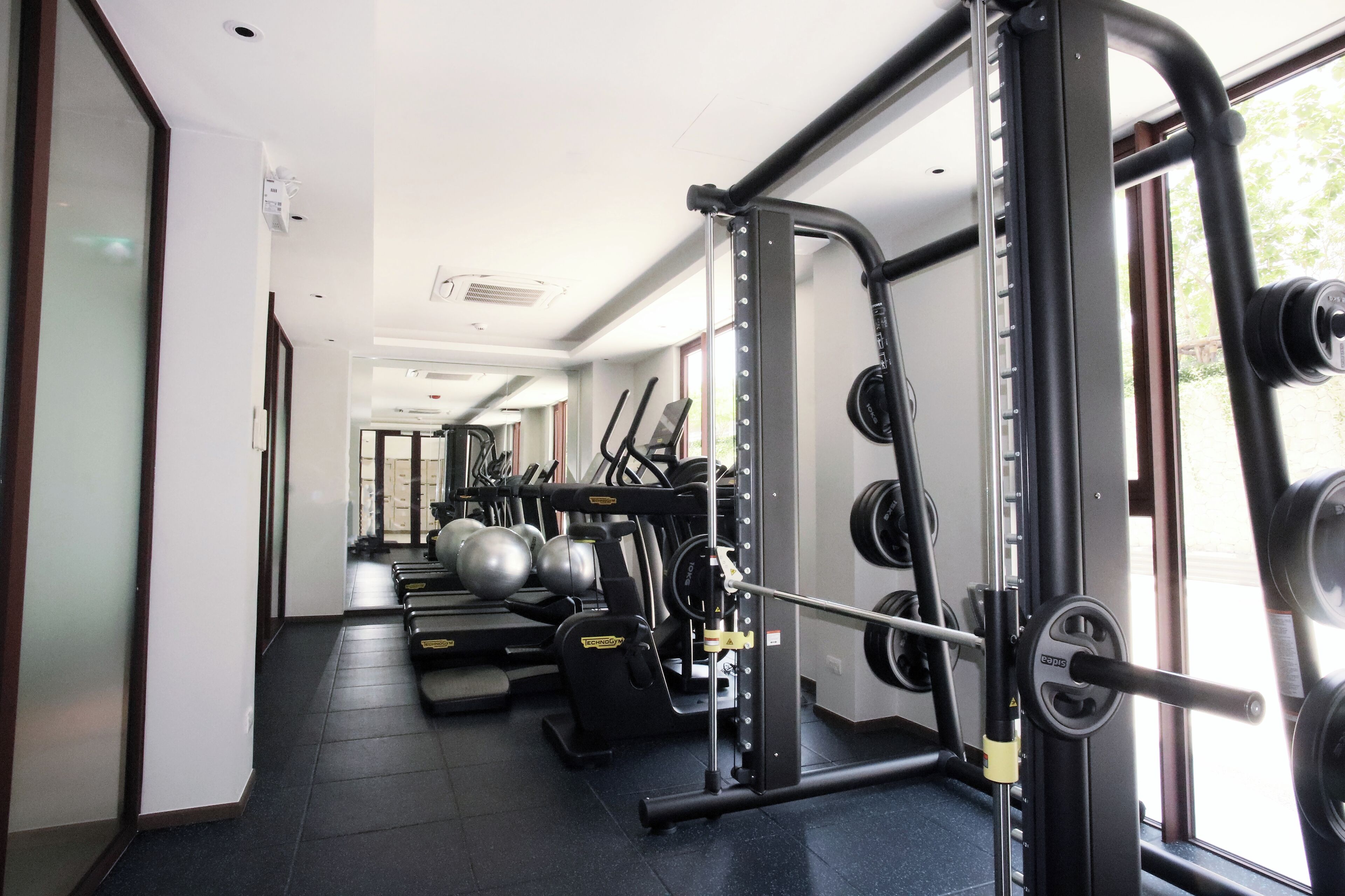 Un gimnasio con equipamiento de levantamiento de pesas, cintas de correr y pelotas de ejercicio.