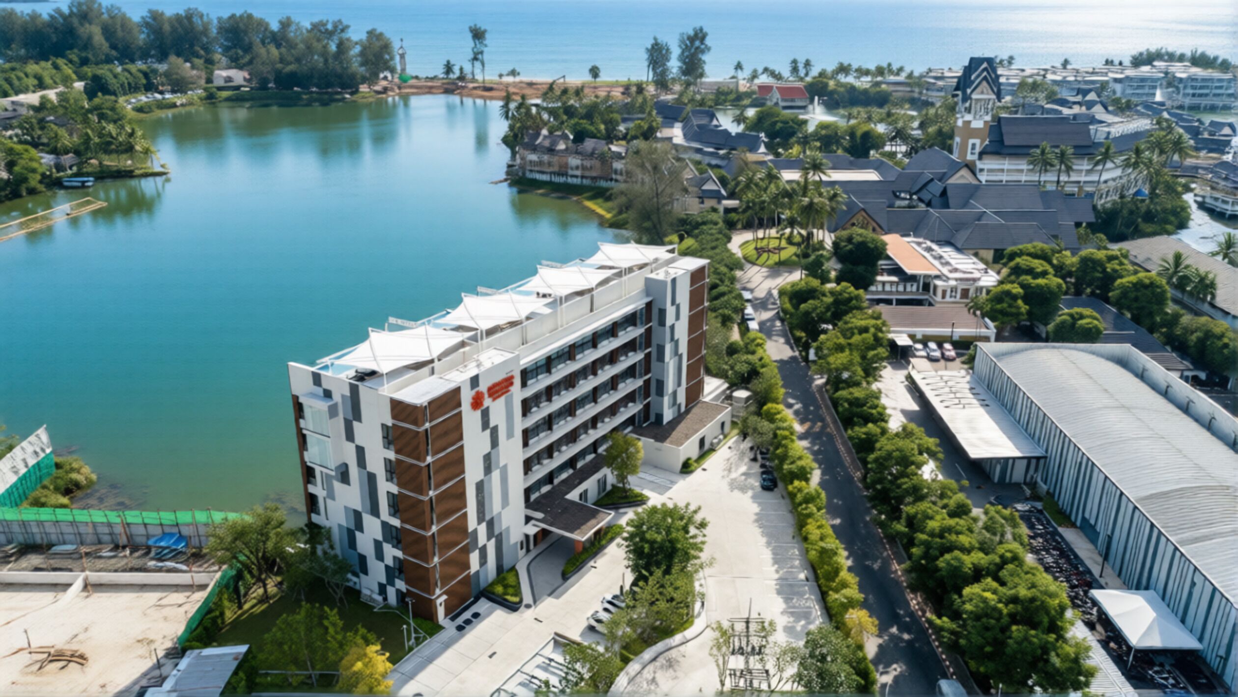 A modern building with a multi-story structure, adjacent to a body of water and surrounded by greenery.