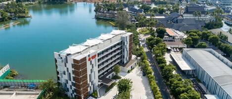 A modern building with a multi-story structure, adjacent to a body of water and surrounded by greenery.