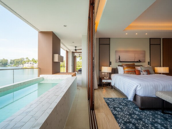 A modern hotel room with a large bed, bedside lamps, a painting, a view of a pool, and a balcony.