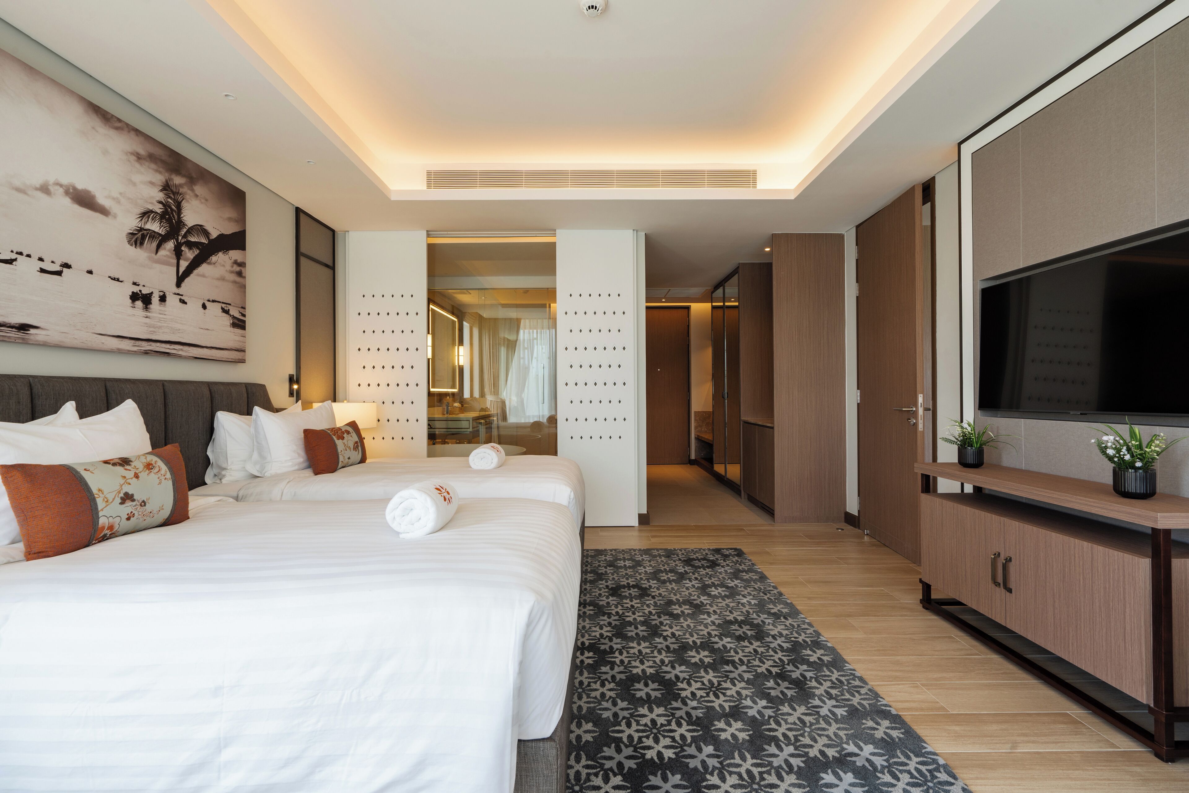 Une chambre d’hôtel moderne dotée d’un grand lit, d’une télévision et d’un dressing.