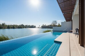 An infinity pool with a clear view of a lake, a covered patio area, and a white building structure. - ANGSANA Oceanview in Laguna area (Choeng Thale)