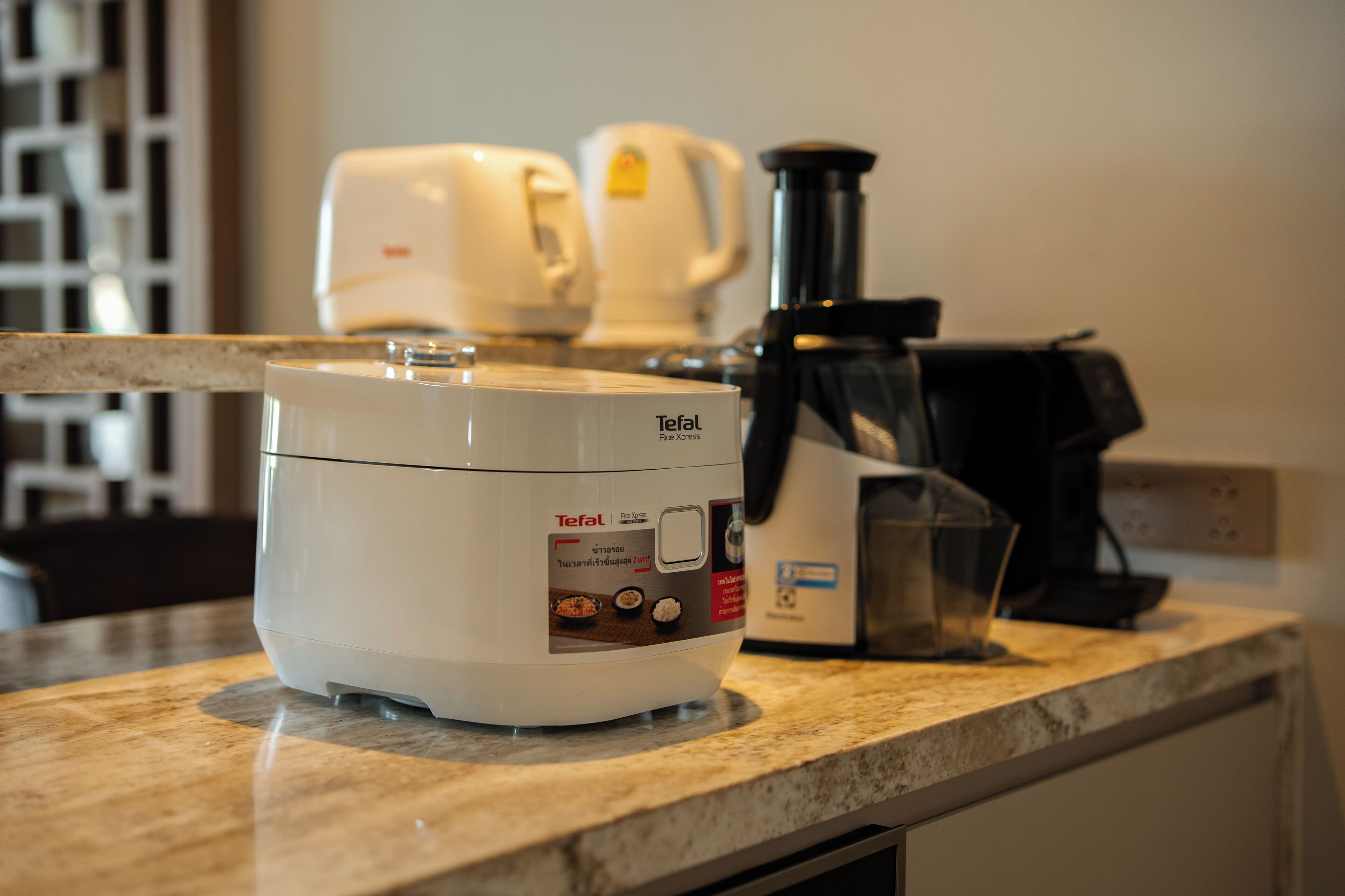 A kitchen with a rice cooker, a coffee maker, and a blender on the counter.