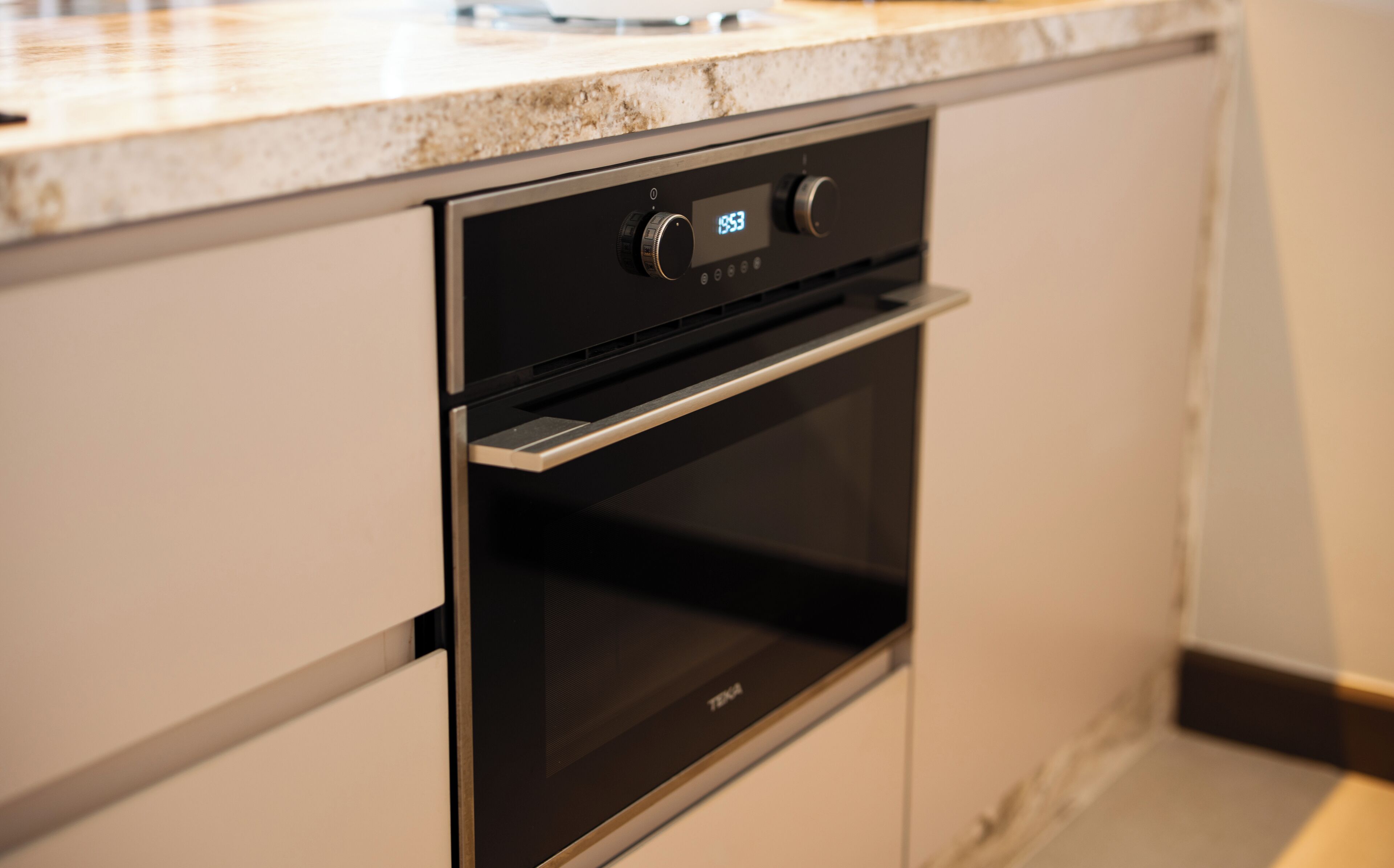 A kitchen with a built-in oven and a digital clock displaying 19:53.