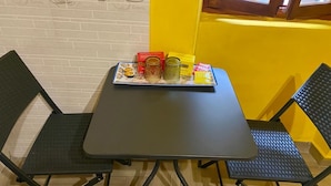 Uma pequena sala de jantar com uma mesa e duas cadeiras, uma janela com vista e uma parede com design inspirado em café.