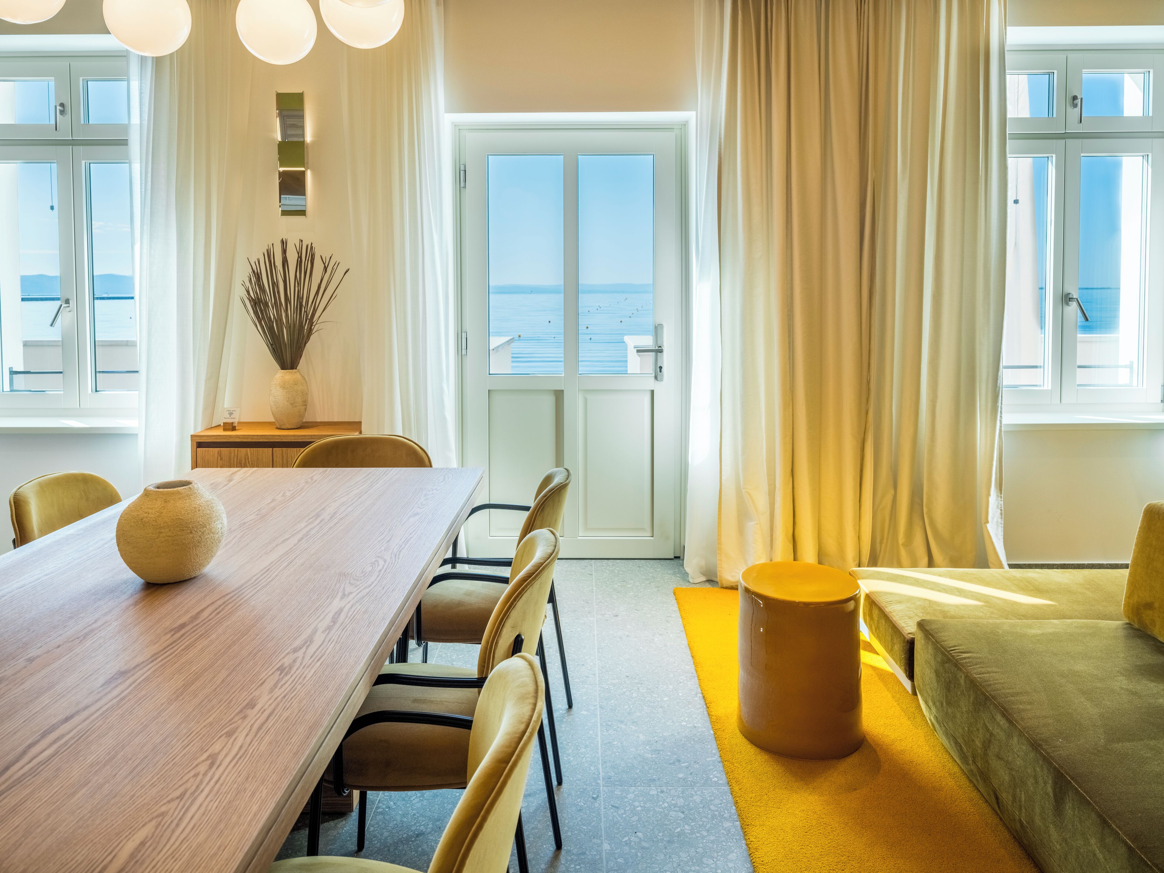 Un espace repas moderne avec une table en bois, des chaises jaunes et un vase.