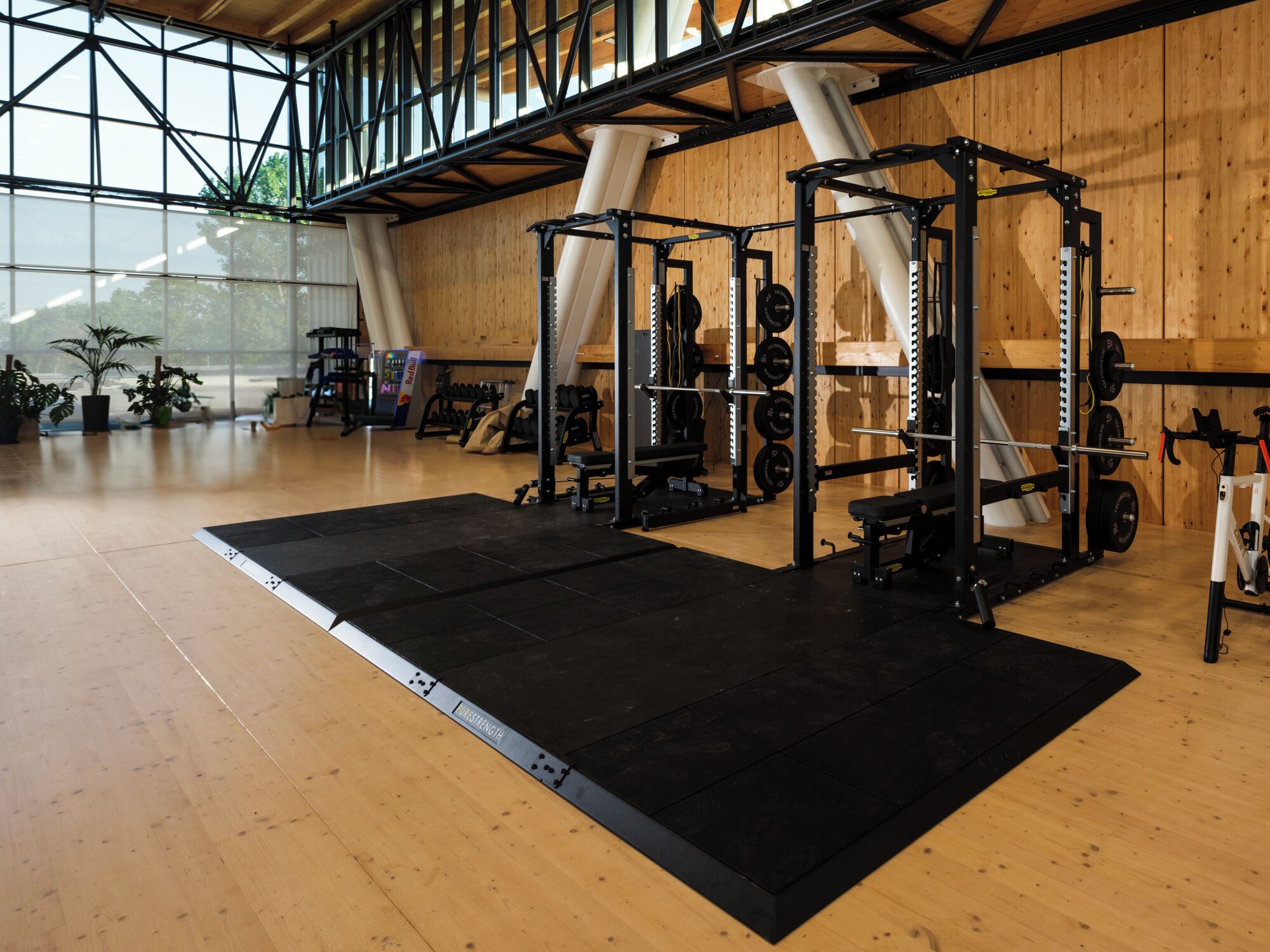 Une salle de sport équipée de matériel de musculation, dotée d’un plancher en bois et de grandes fenêtres.