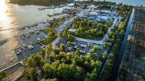 Vue aérienne d’une marina avec des bateaux amarrés, un parking et un bâtiment doté d’un toit plat.