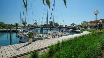 A marina with boats docked, a wooden walkway, and a bridge in the background.