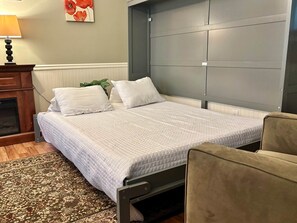 Une chambre à coucher avec un lit, une table de chevet, une lampe, une plante et une chaise.