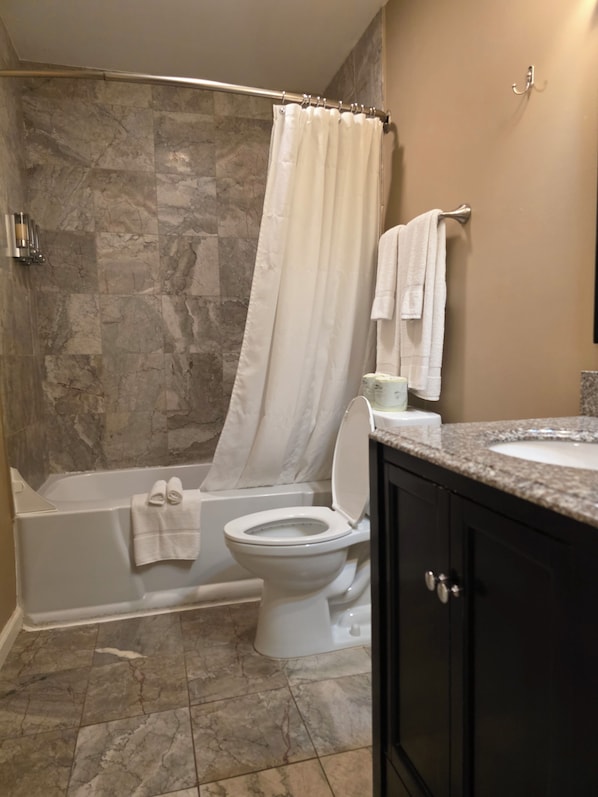 A bathroom with a bathtub, toilet, and a shower curtain.