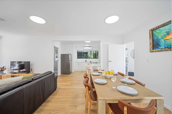 A modern kitchen with white cabinets, a dining table set for four, and a large window.