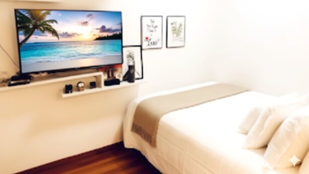Een slaapkamer met een televisie aan de muur, een bed en ingelijste foto's.
