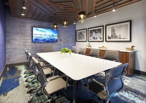A conference room with a large table, chairs, a TV, framed pictures, and a plant. - 2  New Studios with Stunning City Views (Cleveland)