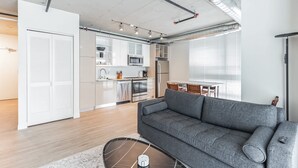 A modern apartment with a grey sofa, a kitchen with white cabinets, and a dining area with a table and chairs. - 10 Brand new combined apartments with city views (Cleveland)