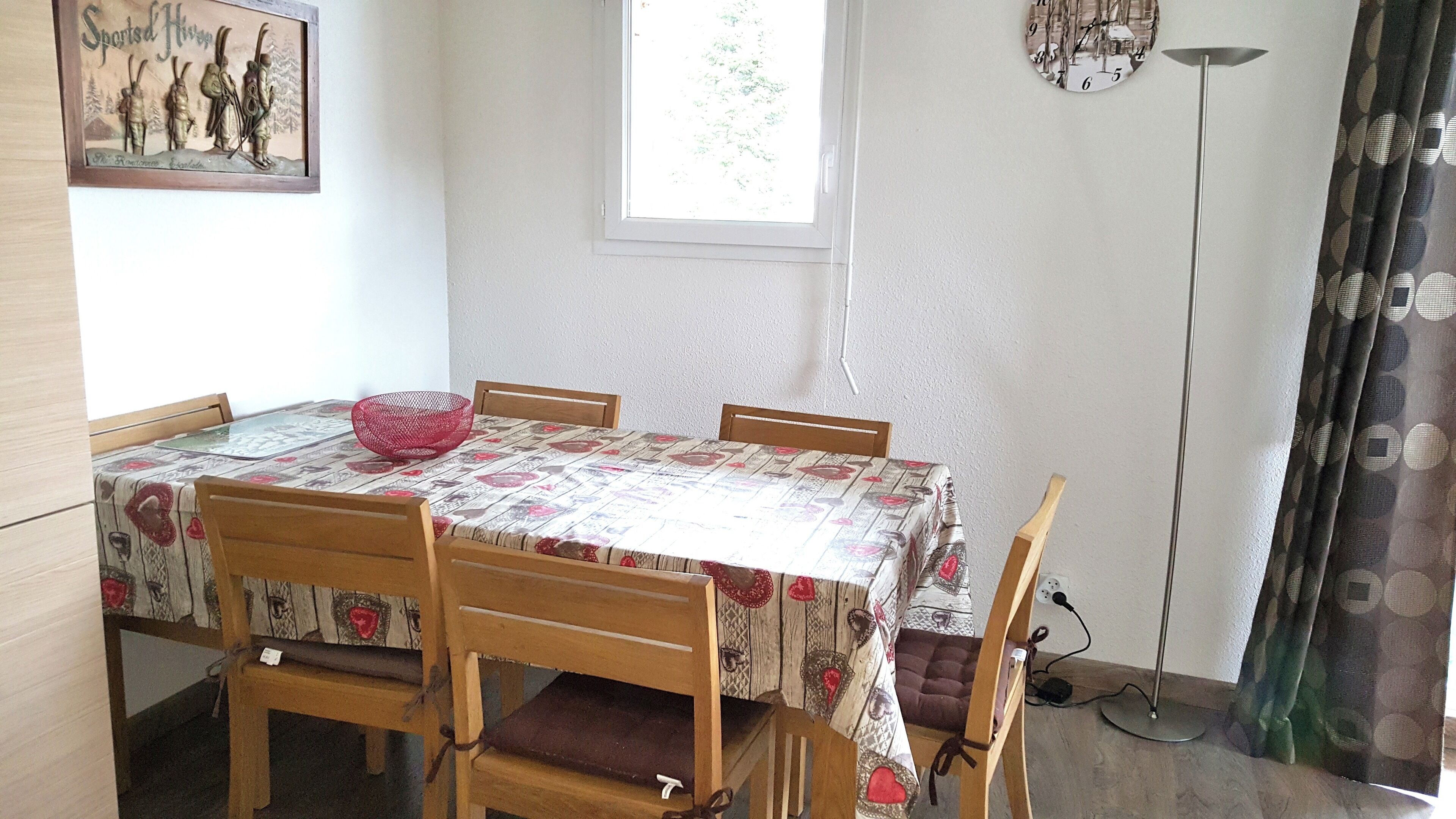 Ein Essbereich mit einem Tisch, bedeckt mit einer gemusterten Tischdecke, umgeben von Holzsesseln.