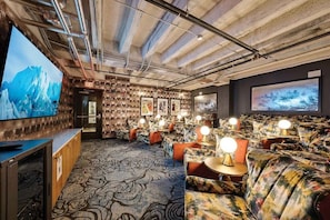 Un espacio lounge acogedor con alfombra estampada, asientos cómodos y obras de arte colgadas en la pared.