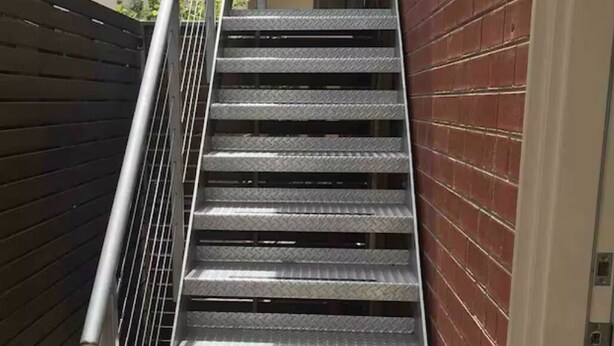 A metal staircase with a handrail, leading to an upper floor.