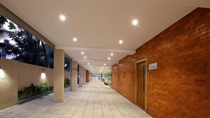 A corridor with tiled flooring, a brick wall on one side, and a door at the end. - PARK RESIDENCY KODUNGALLUR (Kodungallur)