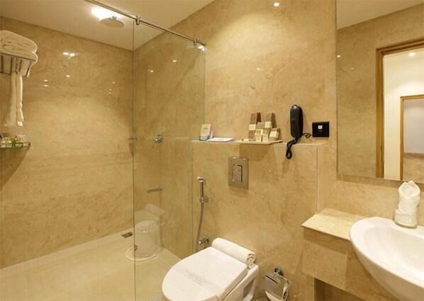 A modern bathroom with a glass-enclosed shower, a toilet, and a sink.