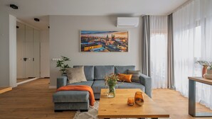 Una sala de estar moderna con un sofá gris, una mesa de centro de madera y un cuadro de un paisaje urbano en la pared.