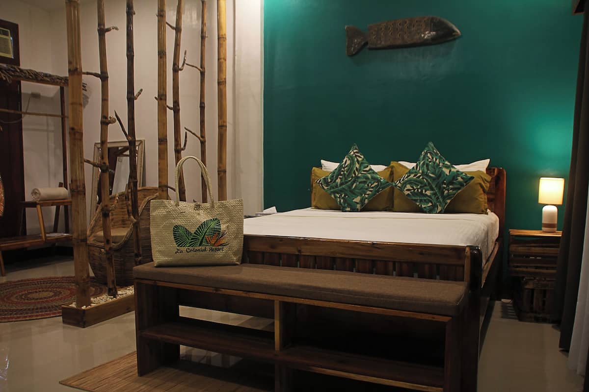 Una habitación con cama, un banco, un adorno de pez en la pared y una estructura de bambú.