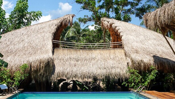 A swimming pool with a thatched roof structure above it. - La Colonial Resort (El Nido)