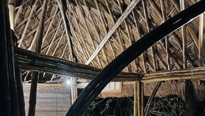 An indoor area with a thatched roof, a reception desk, wicker furniture, and a concrete floor. - La Colonial Resort (El Nido)