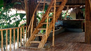 A bamboo staircase leading to a thatched-roof structure with a wooden floor and a metal railing. - La Colonial Resort (El Nido)