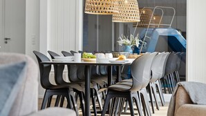 Un comedor moderno con una mesa redonda, sillas negras y lámparas colgantes de mimbre.