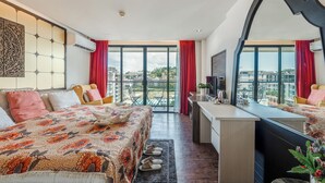 Een hotelkamer met een groot bed, een bureau en een balkon met uitzicht op de stad.
