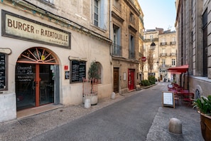 A street view of a restaurant named "Burger et Ratatouille" with outdoor seating and a red awning. - City Balcony (Montpellier)