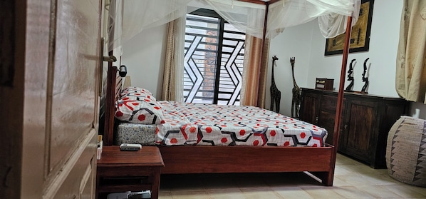 Un dormitorio con cama, mesita de noche y ventana con diseño geométrico.