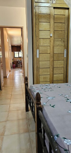 Un dormitorio con estructura de cama de madera, cubrecama floral y armario de madera.