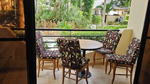 A balcony with a round table and four patterned chairs, overlooking a lush garden and a residential area. - Apartment Saly 3ch - 3sb - Swimming pool - Beach - Veranda (Saly)