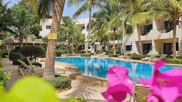 A pool area with lounge chairs, palm trees, and a sign indicating a no swimming zone. - Apartment Saly 3ch - 3sb - Swimming pool - Beach - Veranda (Saly)