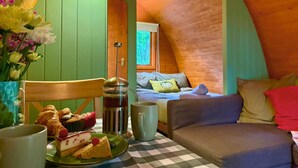 A cozy room with a bed, a table with food, and a window. - Wulfrun Pod (West Stow)