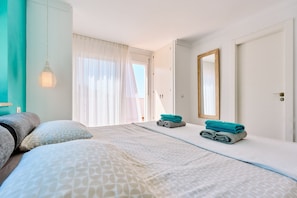 Una habitación de hotel con una cama, un espejo grande y un ventanal con cortinas.