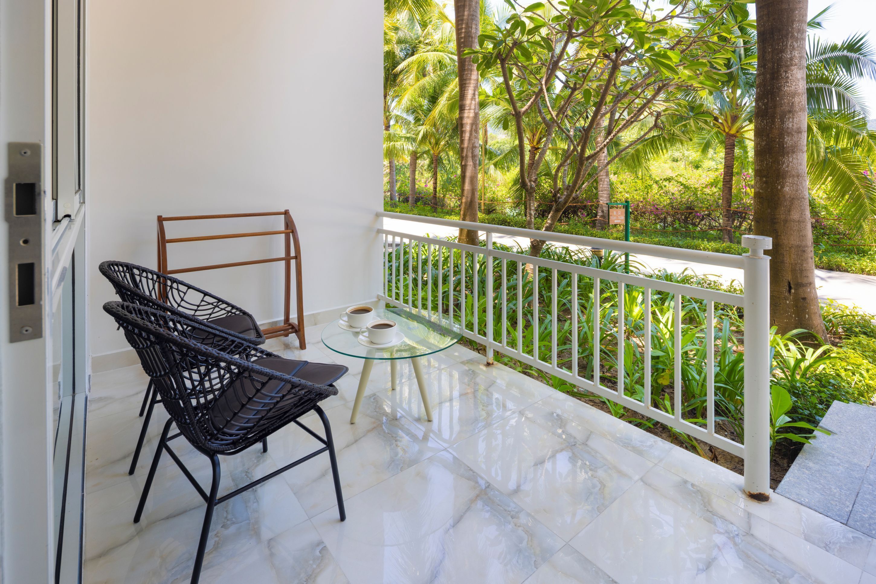 A balcony with a glass table, two chairs, and a white railing.