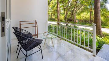 A balcony with a glass table, two chairs, and a white railing.