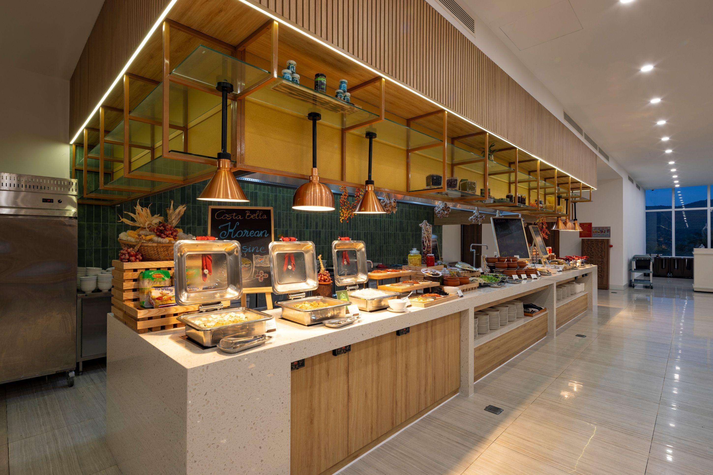Un dispositiu de buffet modern amb una varietat d'aliments, un refrigerador d'acer inoxidable i detalls de fusta.