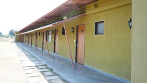 A row of yellow buildings with wooden doors and a covered walkway. - Coconut Lagoon Agro Resort (Parbhani)