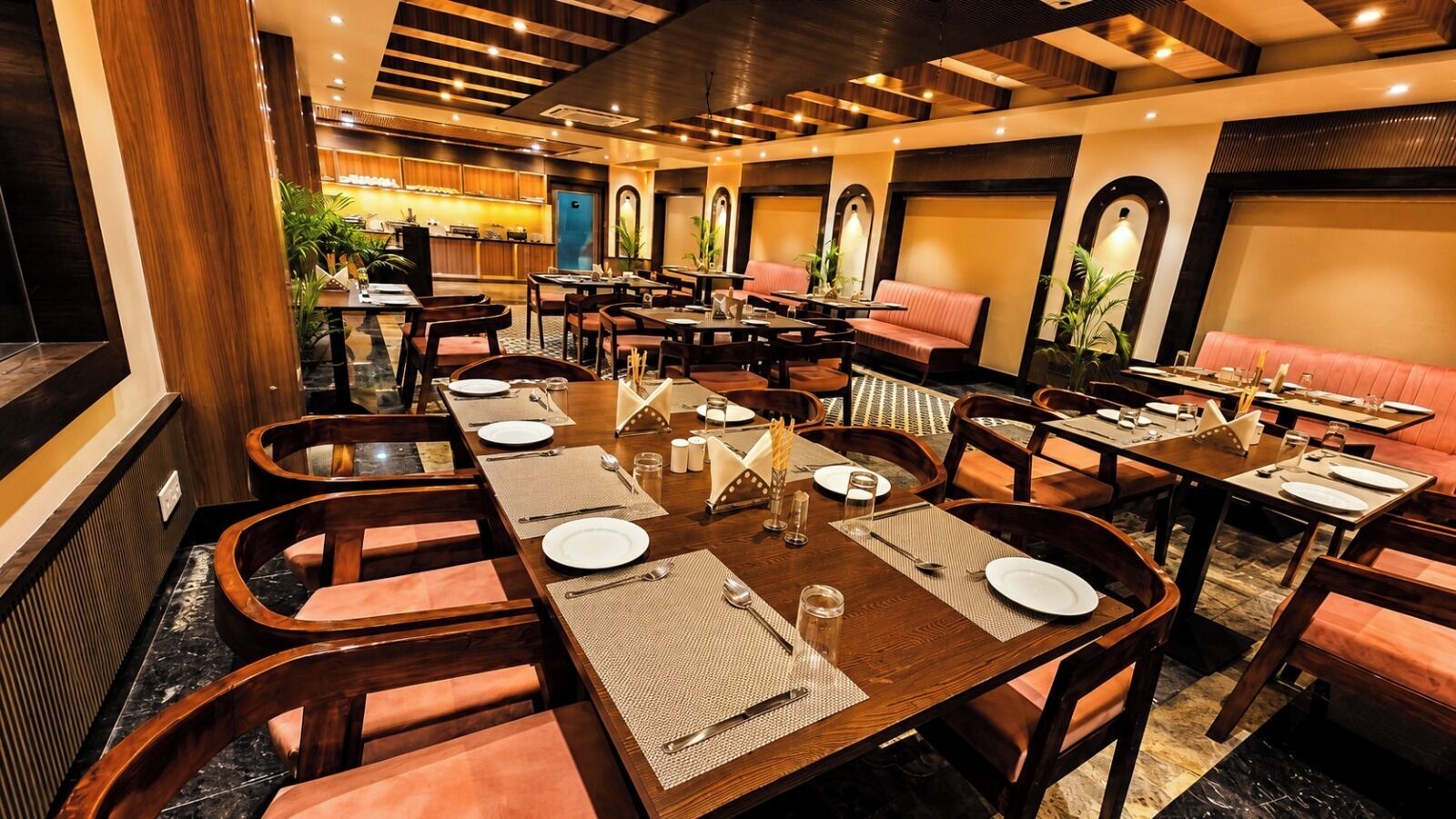 A restaurant with multiple dining tables, chairs, and booths, with a warm ambiance and wooden decor.